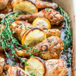 side view shot of lemon garlic chicken legs in a pot with lemon slices and fresh thyme